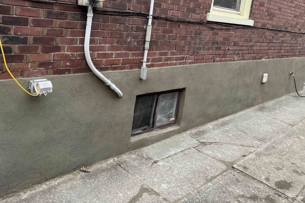 Smooth new parge coat on a brick foundation after repair in Toronto