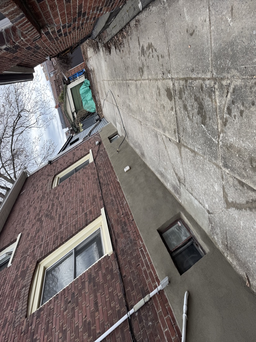 New parge coat running the length of a GTA brick home's foundation beside the driveway