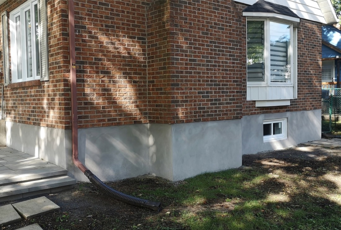 Fresh grey parge coat on the foundation of a red brick Toronto home