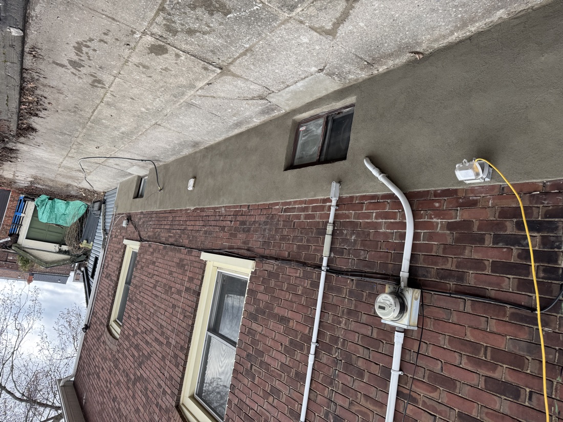 Freshly parged foundation along the side of a GTA brick home, finished neatly around the hydro meter