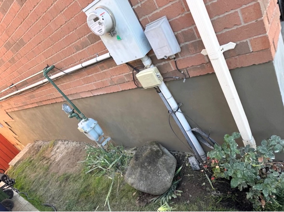 Parged foundation wall finished cleanly around the hydro and gas meters on a Toronto home